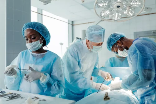 3 doctors working in a hospital and performing an operation to transplant an organ.