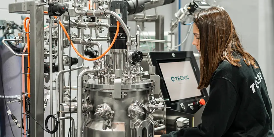 a woman from behind working on a bioprocess equipment (bioreactors)