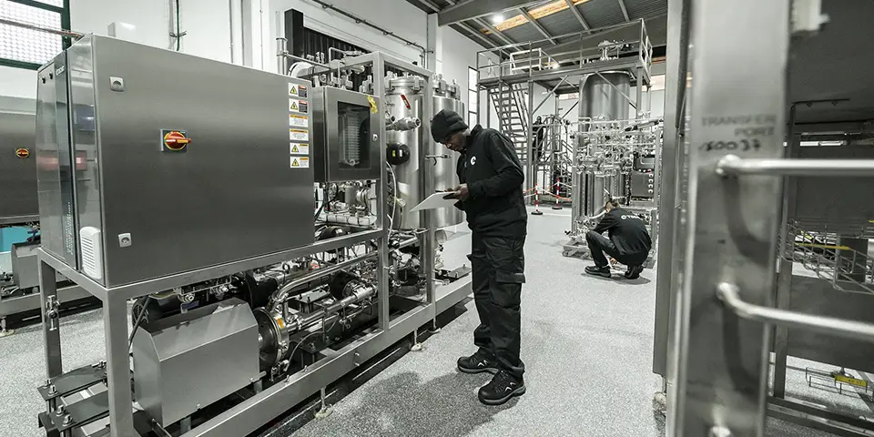 A person working on a FAT hopper with a production scale tangential flow filtration system (tff system).