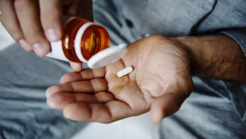 A person's hand holding white medicine