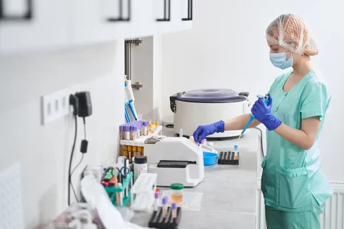 A woman in laboratory security clothes working in the production of drugs.