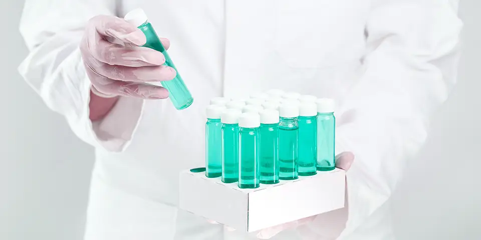 The body of a person in a white coat is seen holding a biotechnology carrier with vaccine solutions.